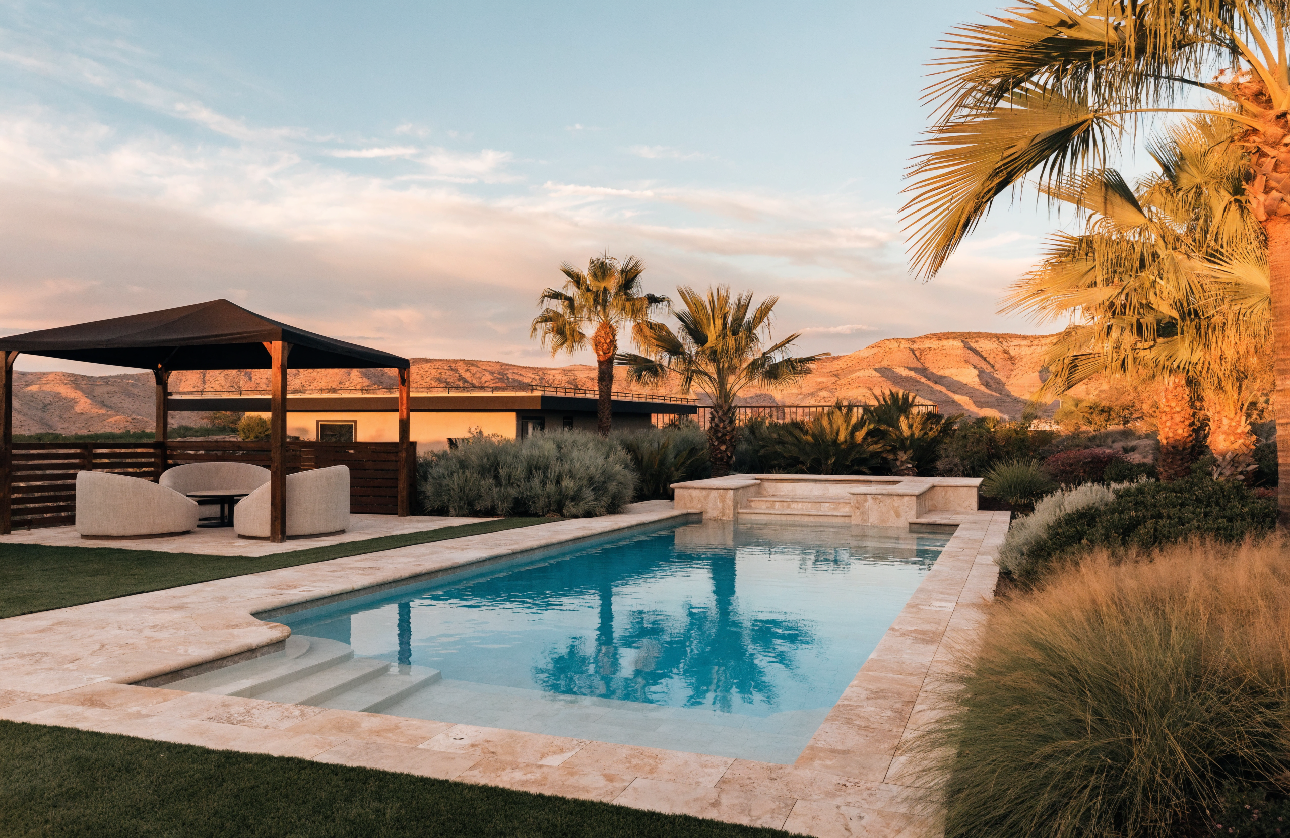 Southern Utah backyard pool with shade cabana, palms and mountain views at golden hour